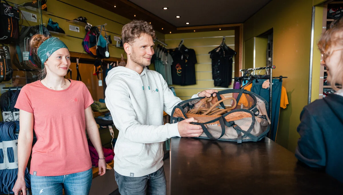 Zwei Personen leihen sich in einer Boulderhalle Ausrüstung aus. | © DAV/Marisa Koch